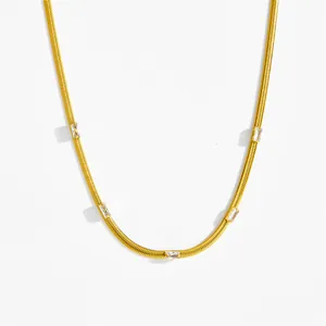 Collana a catena serpente dorata con cinque zirconi rettangolari su sfondo bianco