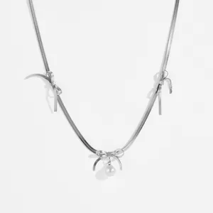 Silver bow necklace with snake chain and hanging white pearl detail on white background