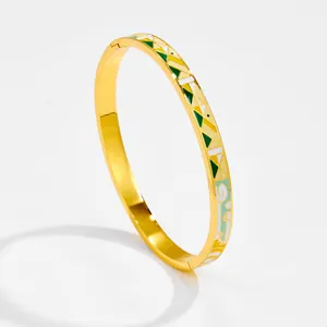 Dettaglio del bracciale rigido dorato vintage con motivi geometrici in smalto colorato