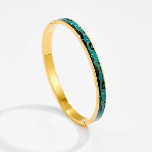 Dettaglio del bracciale rigido smaltato vintage con motivi blu e finitura dorata