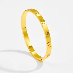 Detailed view of gold bangle featuring alternating zircon stones and clover patterns