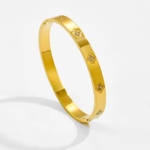 Close-up of gold starburst bracelet with zircon clover motifs and brushed metal texture