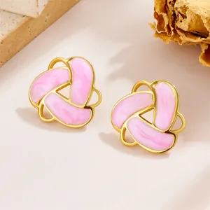 Detailed close-up of vintage geometric gold knot earrings with pink marble enamel inlay