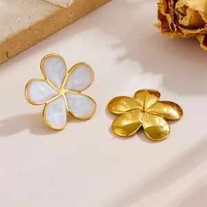 Detailed view of gold stainless steel floral stud earrings with white enamel finish