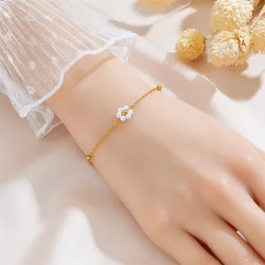 Close-up of a gold pearl flower bracelet worn by a model with elegant lace sleeves