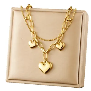Double-layer gold stainless steel chain bracelet with three heart pendants on a display pad
