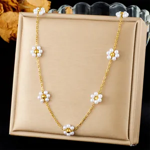 Close-up of gold stainless steel necklace with delicate pearl flower charms on a stand
