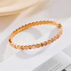 Detail van een gouden titanium armband met geometrisch honingraatmotief en zirkonia's