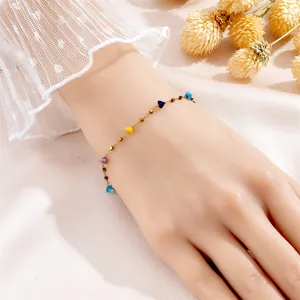 Elegant gold bracelet with multicolored gemstones worn on a wrist over pink silk