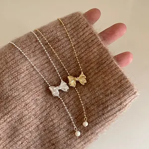 Vintage gold and silver beaded necklaces with bow pendant and pearl on cozy sweater cuff