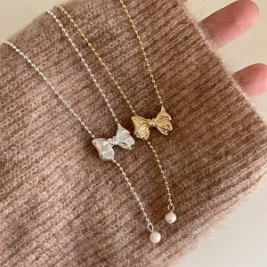 Close-up of vintage metallic bow necklace with pearl pendant in gold and silver options