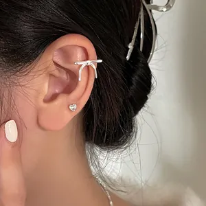 Silver bow ear cuff for women with a minimalist metallic design and heart earring detail