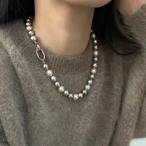 Elegante collana di perle multicolore con chiusura in metallo su maglione marrone
