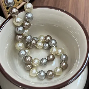 Dettaglio di eleganti perle champagne, grigie e marroni in una tazza di ceramica