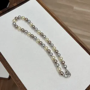 Dettaglio della collana di perle multicolore con sfumature champagne, argento e marrone