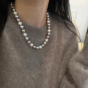 Dettaglio della collana di perle sfumate colorate indossata su un maglione marrone