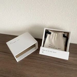 Boîte à bijoux texturée avec pochon en coton blanc sur une table en bois naturel