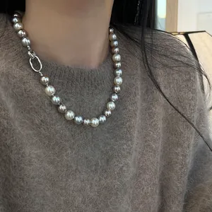 Dettaglio collana di perle multicolore con chiusura d'argento su maglione di mohair marrone