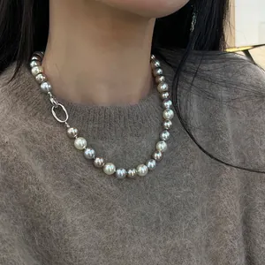 Dettaglio di una collana di perle multicolore sfumate su un maglione marrone caldo