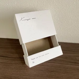 Détail d'un coffret à bijoux blanc coulissant avec texture papier écolo et logo noir