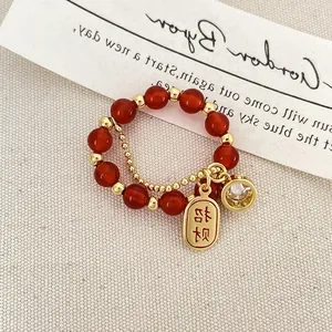 Detalle macro de anillo de cuentas con ágata roja y colgantes de suerte Zhao Cai