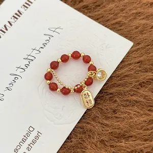 Detalle de anillo de ágata roja con amuleto de suerte y colgante de circón brillante