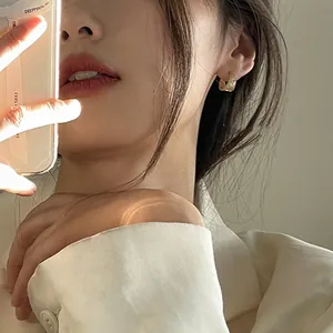Close-up of elegant gold textured hoop earrings worn by a model in soft lighting