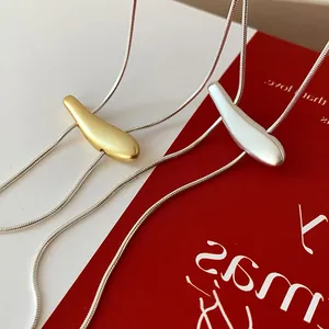 Detail of matte gold and silver teardrop pendants on elegant snake chains