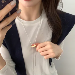 Minimalist matte mixed metal lariat necklace featuring a gold organic pendant on silver chain