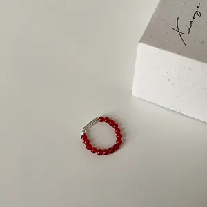 Nahaufnahme eines elastischen Perlenrings aus rotem Achat mit silberner Metallröhre