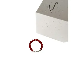 Eleganter elastischer Ring mit roten Achatperlen und Silberakzenten auf weißem Hintergrund