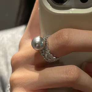 Détail macro d'une bague large argentée avec perle grise et sertissage de zircons