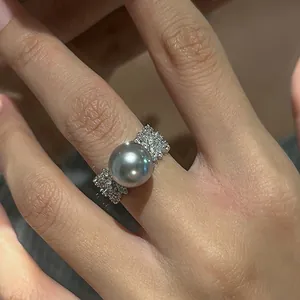 Détail macro d'une bague large texturée avec une grande perle grise sur un doigt