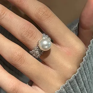 Gros plan détaillé d'une bague large avec une grande perle blanche et pavage de zircons