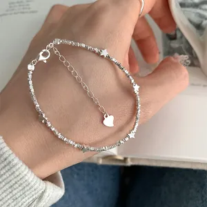 Detailed shot of star charms and heart pendant on silver bead bracelet worn on wrist
