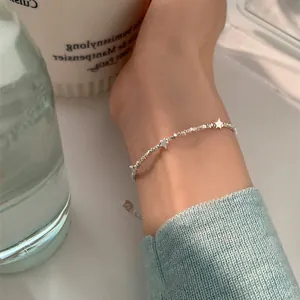 Detailed view of silver star charms and irregular beads anklet worn on the ankle