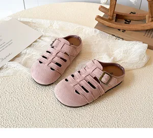 Pink hollow-out suede girls' sandals with buckled straps on a decorative white surface