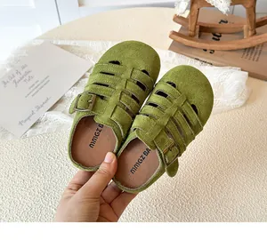 Detail of green suede hollow-out toddler sandals with vintage buckle on lace background