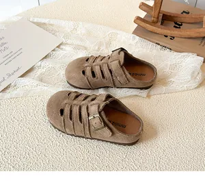 Close-up of brown suede hollow-out girls' clogs with adjustable metal buckle strap