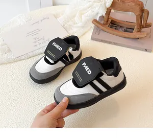 Détail de baskets filles avec bande velcro et design patchwork en noir et blanc