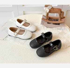 Detailansicht weißer und schwarzer Mädchen-Mary-Janes mit Webstruktur und Gold-Schnallen