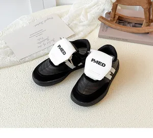 Détail de baskets pour enfants en cuir avec fermeture velcro et logo PAED brodé