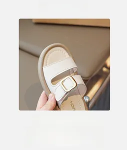 Detail of girls' cream sandals showing leather texture and gold buckle decoration