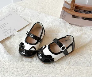 Detail von Mädchen Mary Janes mit Schleife und Bären-Schnalle auf weißem Spitzenhintergrund