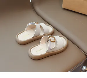 Detail of girls' sandals with cream straps, gold buckles, and thick brown soles