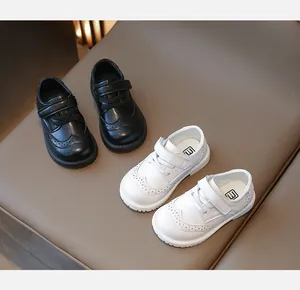 Close-up of black and white girls' brogue leather shoes with velcro and carved details