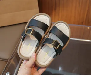Detail of girls' black pebbled leather sandals with gold buckles and soft soles
