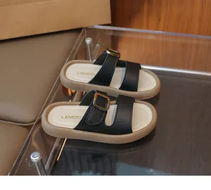 Close-up of black leather girls' sandals with gold buckles and soft thick soles