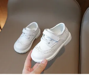 Macro shot of white leather girls shoes with brogue details and velcro strap