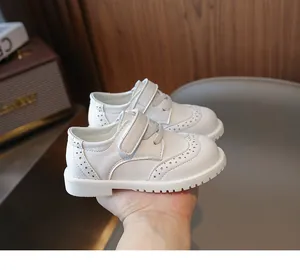 Close-up of white girls brogue shoes with decorative perforation and velcro strap